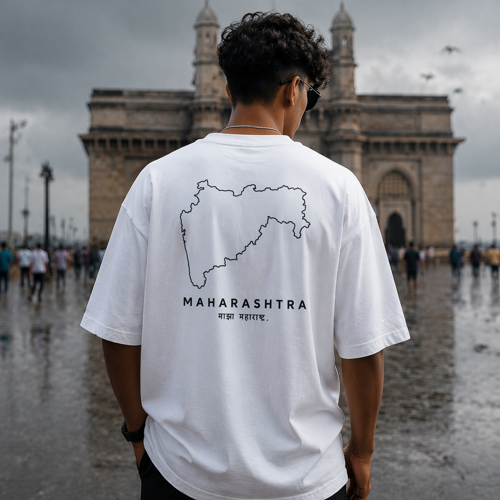 Person wearing a white t-shirt with 'Maharashtra' design in front of a large architectural structure.